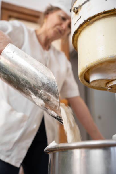 istock Unrecognizable baker woman adding flour into an industrial beater 1275246552