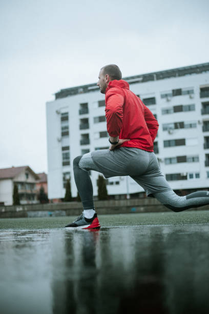 istock Man in red wind jacket is stretching on rainy day 1275246567
