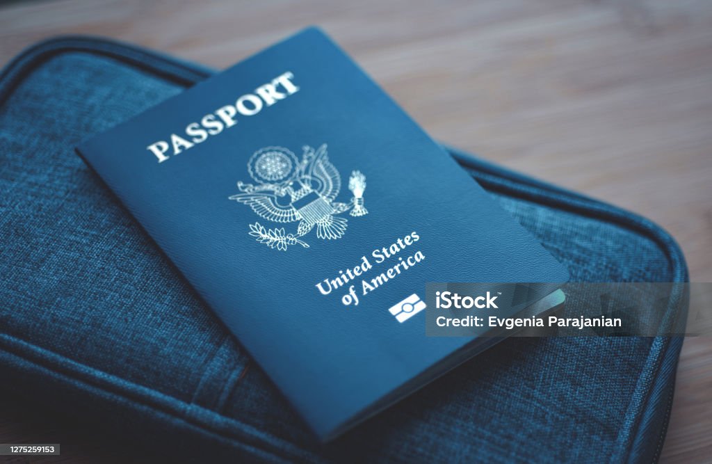 USA (United States of America) Passport on blue travel wallet, wooden background. Top View (above) Passport of USA (United States of America) on blue travel wallet, wooden background. Close up. Passport Stock Photo