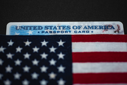 Passport card of United States of America covered in Flag of USA on black background.