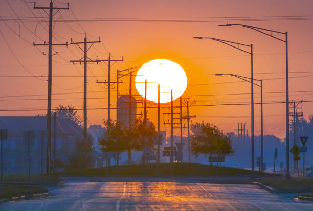 Big telephoto sunrise through city clutter, utility poles and lines.