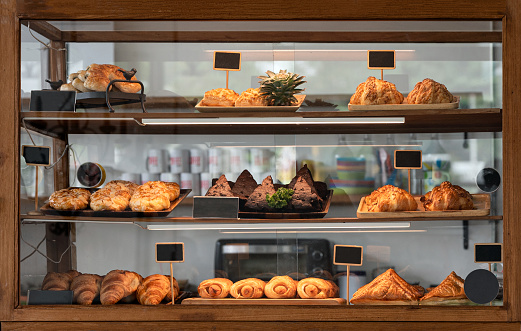 Variety baked bread and dessert in glass showcase at bakery cafe
