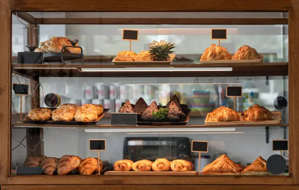 Photo of Variety baked bread and dessert in glass showcase at bakery