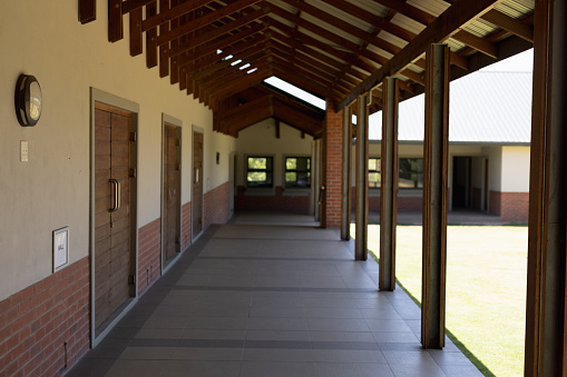 Empty exterior corridor of an elementary school building with a stone wall style, on sunny day.