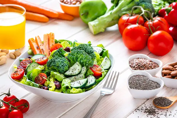 Photo of Vegan food: healthy salad plate on white table.