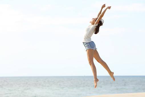 Mujer emocionada con piernas largas saltando en la playa photo