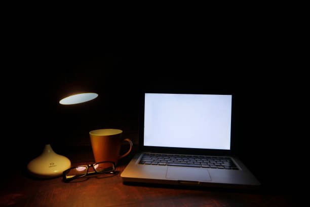 laptop with blank screen with table lamp on desk .