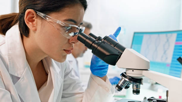 istock Asian, female scientist with microscope. Brainwave scanning research on computer. Team in background 1275317163