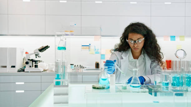African, female scientist working on laboratory glassware Modern laboratory interior.  African ethnicity woman working on medical samples in background science research stock pictures, royalty-free photos & images