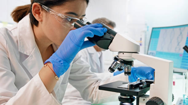 istock Asian, female scientist with microscope. Brainwave scanning research on computer. Team in background 1275317318