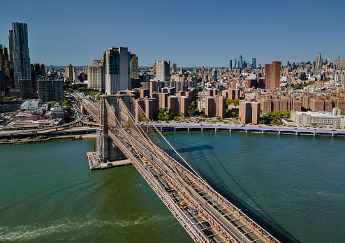 Flying backward view of across Brooklyn Bridge through the East river to Manhattan district U.S.