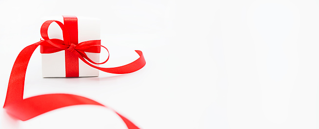 white gift box with red ribbon and bow on a white background. Space for text. Banner