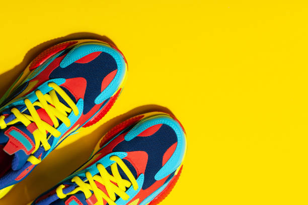istock Multicolor sport shoes on yellow background with shadows 1275324002