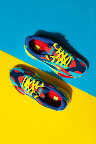 istock Multicolor sport shoes on yellow background with shadows 1275324292