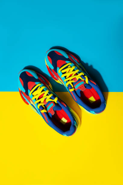 istock Multicolor sport shoes on yellow background with shadows 1275324527