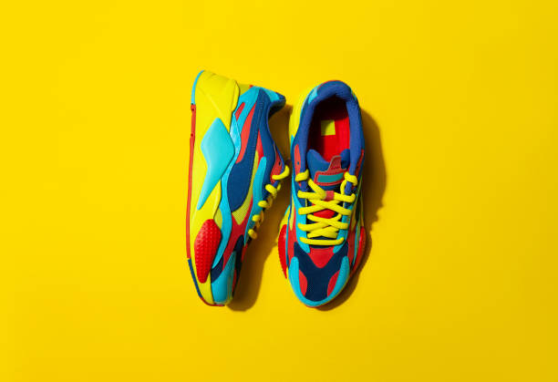 istock Multicolor sport shoes on yellow background with shadows 1275324634