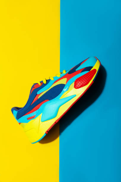 istock Multicolor sport shoes on yellow background with shadows 1275324655