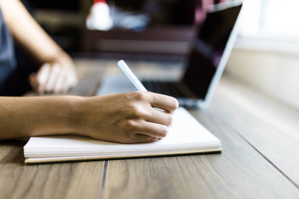 istock Young woman working on laptop and taking a note 1275326762
