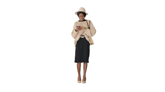 Wide shot. Front view. Pretty african american woman in knitted sweater and white hat answering her phone on white background. Professional shot in 4K resolution. 046. You can use it e.g. in your medical, commercial video, business, presentation, broadcast