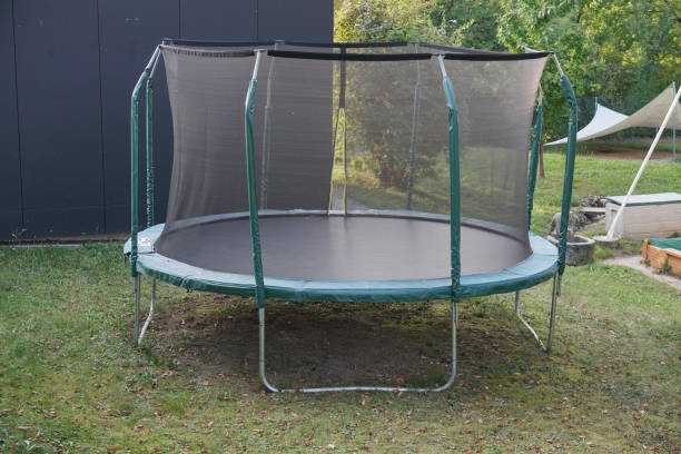 istock Empty green trampoline with safety net on the lawn in garden. 1275353099