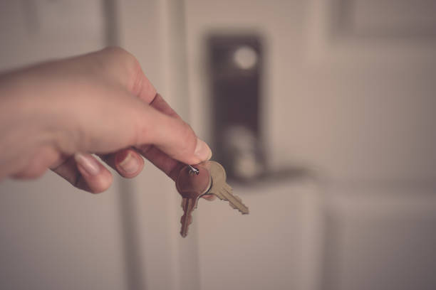 Woman's hand holding two metal keys on door with locker background. stock photo