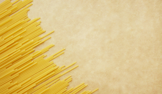Italian spaghetti pasta on craft paper background with copy space. Top view