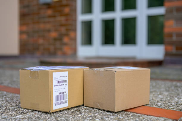 Close-up of cardboard packages laying on floor in front of a house during coronavirus pandemic.