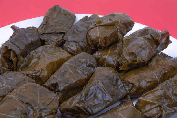 istock Vegetarian Dolma, stuffed grape leaves with rice on white dish on red surface. . 1275409065