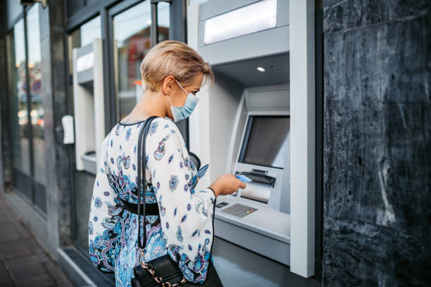 istock Withdrawing money at the ATM with face mask on 1275409370