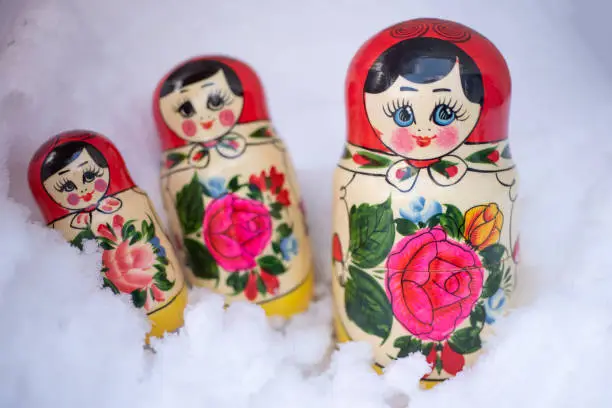 Photo of Three Traditional russian wooden nesting dolls Matryoshka arranged in the real glittering snow.