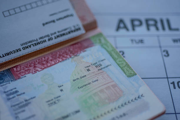 H1B visa stamp in passport, blurred april calendar on background. H1B visa program deadline concept. stock photo