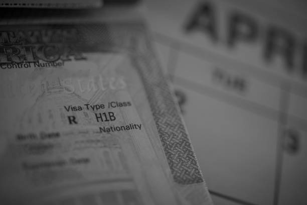 H1B visa (for specialty workers) stamp in passport, blurred april calendar on background. H1B visa program deadline concept. Close up view. stock photo