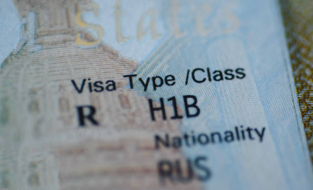 Fragment of H1B visa (for specialty workers) stamp in passport, blurred april calendar on background. H1B visa program deadline concept. Close up view. stock photo
