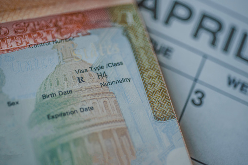 An H-4 visa (immediate family members of the H-1B visa holders) stamp in passport on blurred april calendar background.   H4 visa program deadline concept. Close up view.
