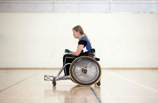 a portrait of a woman with a disability sitting in a wheelchair waiting for a basketball game to begin. Selective focus. High quality photo