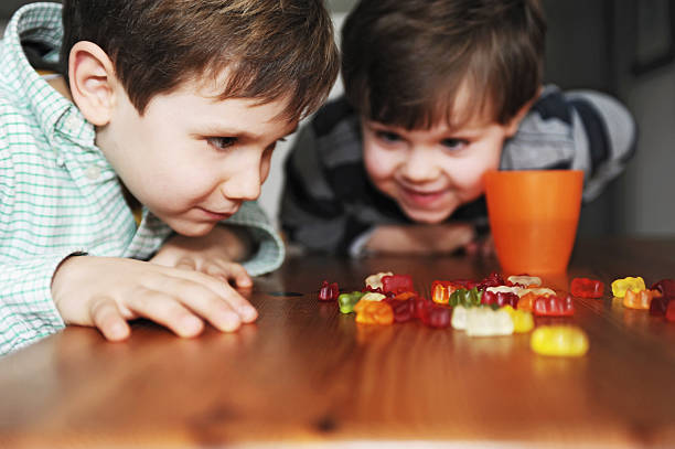 jungen spielen mit süßigkeiten auf tisch - gummibärchen stock-fotos und bilder