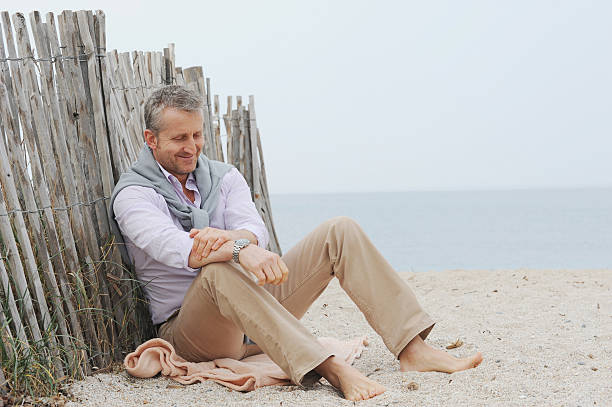 uomo seduto nella sabbia sulla spiaggia - fey foto e immagini stock