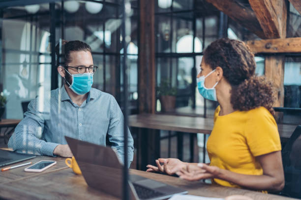istock Business persons in a conversation wearing face masks 1275441409