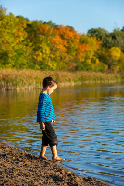 istock Boy Walking In Water at Beach on Autumn Day 1275443291