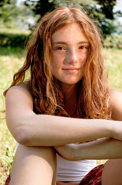 mädchen sitzen auf gras im garten - weiblicher teenager allein stock-fotos und bilder