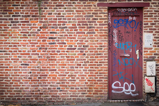 LILLE, FRANCE - July 18, 2013. A brick wall and door with graffiti writing on a side street in Lille, France. Ideal for urban grunge background or template