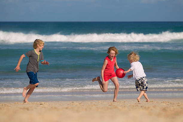 kinder spielen mit roten ball am strand - @jackstar stock-fotos und bilder