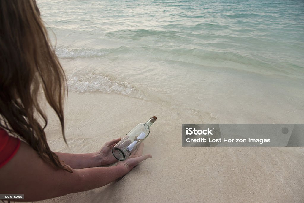 Femme avec message dans une bouteille sur la plage - Photo de Message dans une bouteille libre de droits