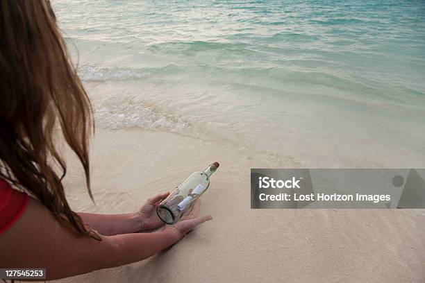 Photo libre de droit de Femme Avec Message Dans Une Bouteille Sur La Plage banque d'images et plus d'images libres de droit de Message dans une bouteille - Message dans une bouteille, Trouver, Femmes