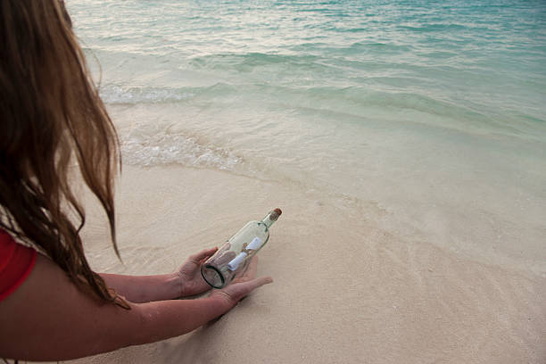 mulher com mensagem em uma garrafa na praia - lost beach - fotografias e filmes do acervo