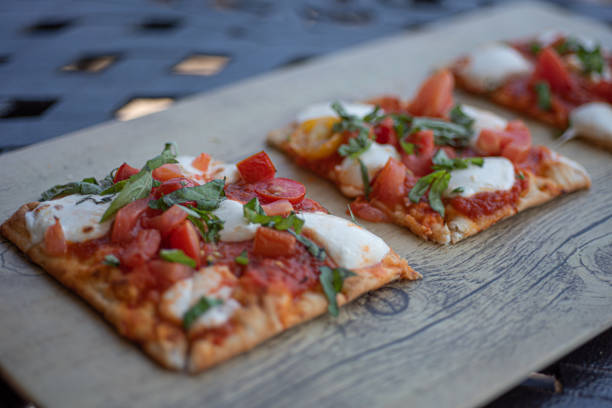 Three pieces of Classic Margherita Flatbread Pizza on wooden board stock photo