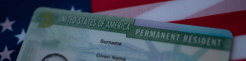 Fragment of Permanent Resident Green card  of United states of America on flag of USA. Above close up view. Wide photo.
