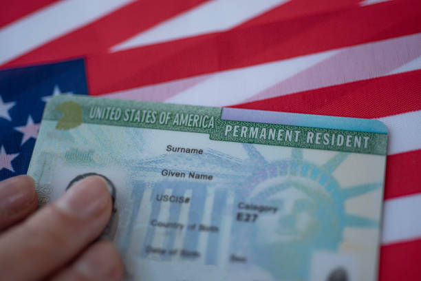 Permanent Resident Green card  of United states of America on flag of USA. stock photo