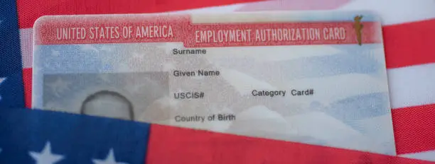 Photo of Employment Authorization card on USA Flag surface. Close up view.
