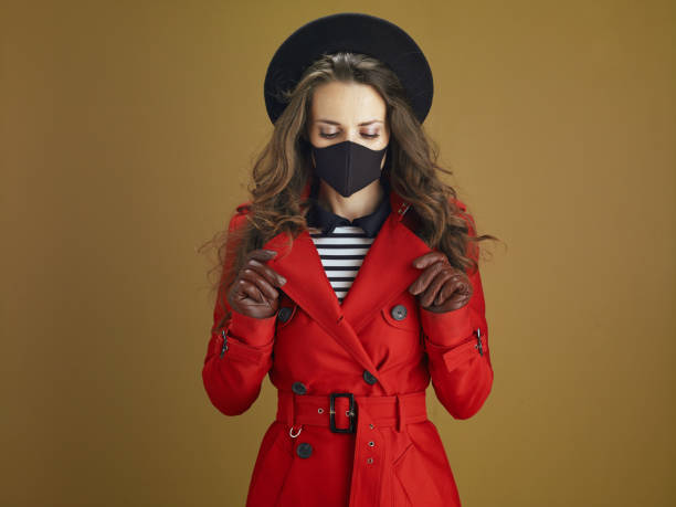 istock relaxed modern woman in red coat on bronze background 1275465368